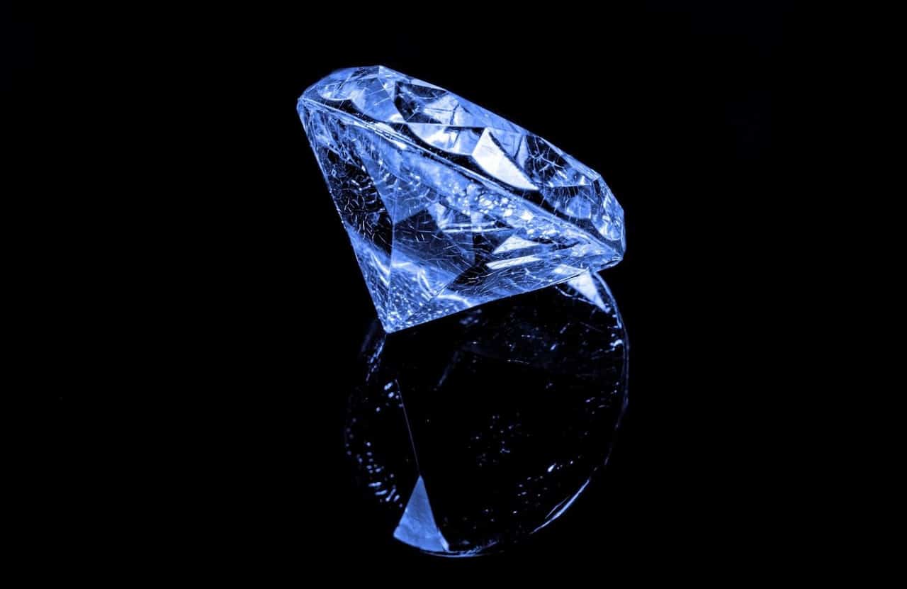A diamond and its reflection on the dark background